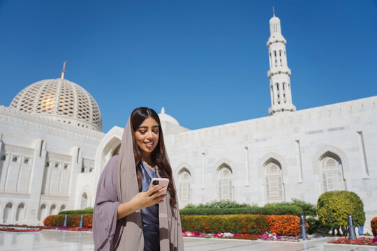 Omani woman using smartphone at sultan qaboos grand mosque