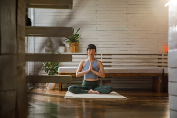 Active young female meditating in living room at home