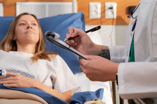 Doctor taking notes on clipboard while visiting patient