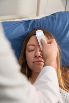 Doctor measuring patient's temperature contactless thermometer