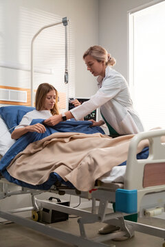 Doctor giving water to patient lying in hospital bed