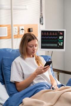 Patient using smartphone while resting in hospital bed