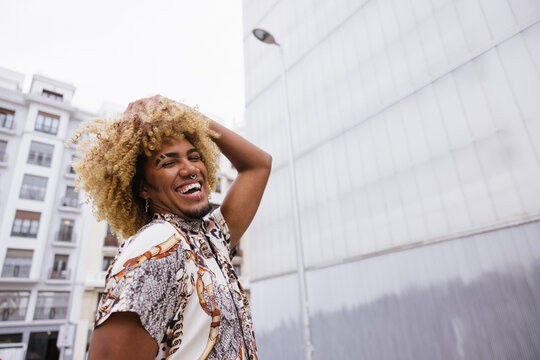 Joyful gay man with curly hair enjoying an urban setting