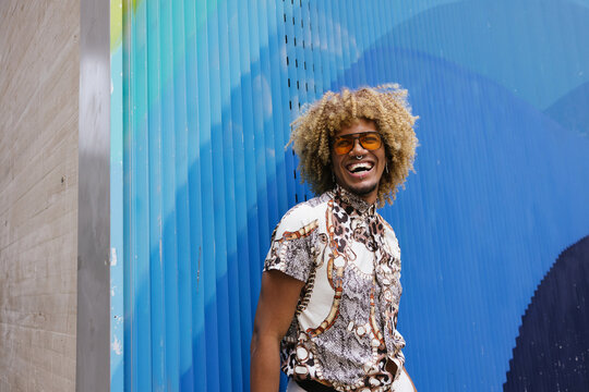 Vibrant Colombian gay man Smiling Against Blue Artistic Wall