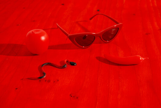 Monochrome still life with toy snake, apple, pepper, and sunglasses