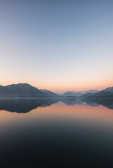 Obraz premium Tranquil Sunset Reflection Over Serene Lake Surrounded by Majestic Mountains