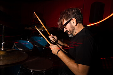 Intense drummer immersed in music under vibrant stage lights