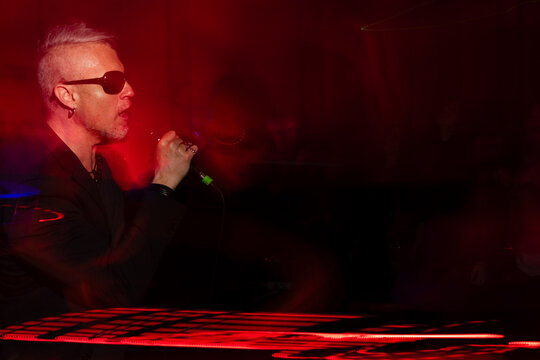 Energetic singer performing under vibrant red stage lights