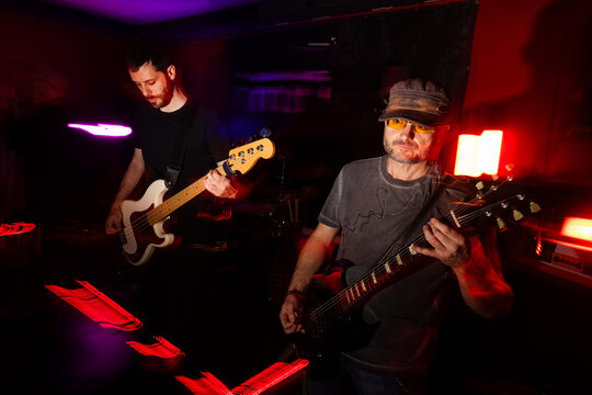 Musicians Playing Electric Guitar and Bass in Vibrant Lighting