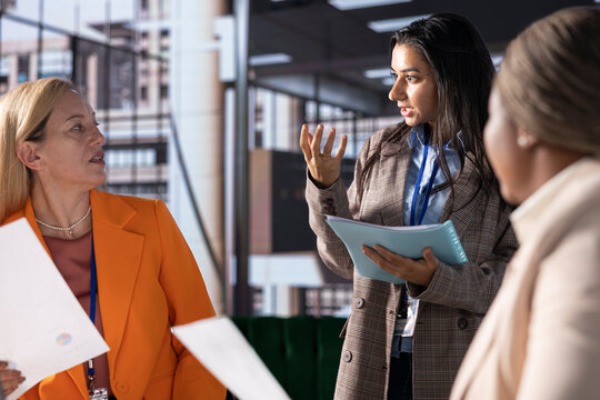 Multiethnic women executives uniting forces in a collaborative meeting, focused on data management and business development. Experts with leadership skills fighting for empowerment.