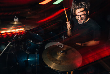 Passionate drummer performing on stage with vibrant lights