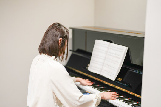 A Japanese woman in her 30s is playing the piano at home.