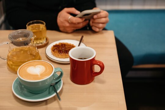 anonymous man sitting at table with coffee and tea