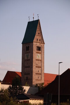 A clock tower in Oberg&uuml;nzburg with a green roof and a cross on top