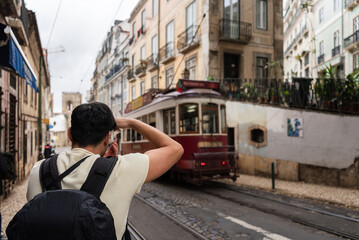 Tourist taking photo of traditional tram in lisbon, portugal