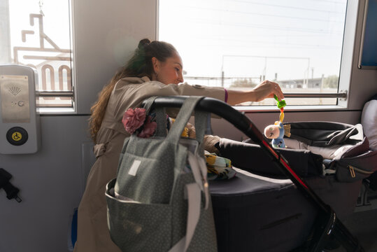 Mother entertaining baby with toy on train during trip