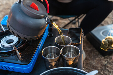 Pouring Tea From Camping Kettle Into Metal Cups