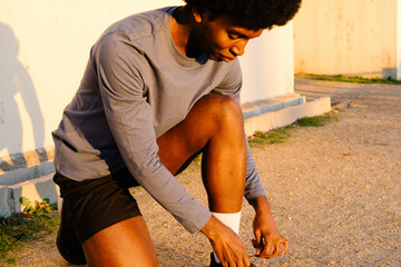 Fit man kneeling on a gravel path lacing up his sneakers