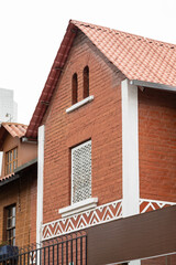 A brick house with a triangular roof and small square windows. The traditional design combines rustic elements with a cozy, charming appearance, offering a timeless and inviting home aesthetic.