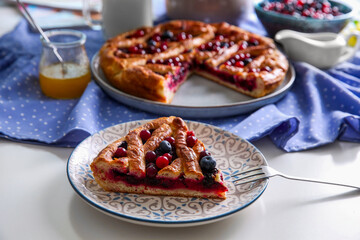 Piece of delicious currant pie with fresh berries served on white table