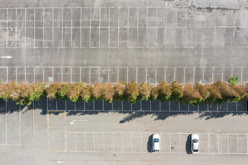 Aerial view of empty parking lot with two cars and trees