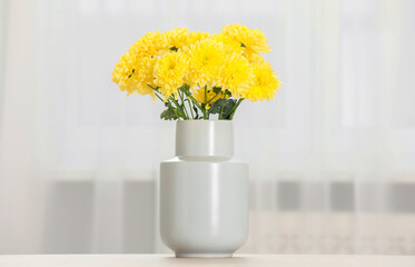 Beautiful yellow flowers in vase on table at home