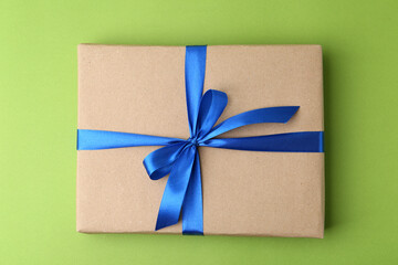 Gift box with blue bow on green background, top view