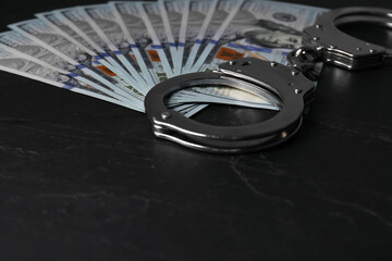 Corruption. Dollar banknotes and handcuffs on black table, closeup