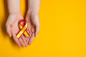 Woman with colorful ribbon on yellow background, top view and space for text. Hepatitis C awareness