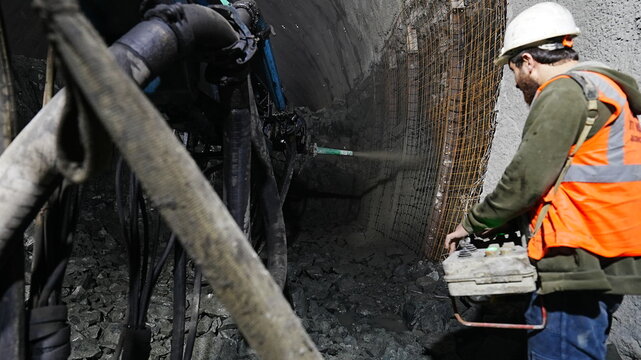 A worker commands concrete spraying on a wall with a remote control