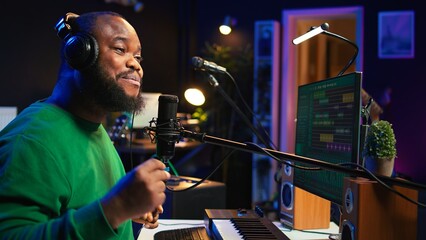 Confident artist singer performing a song on microphone in home studio, recording his audio files...