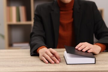 Signing autograph. Writer with pen and book at wooden table indoors, closeup