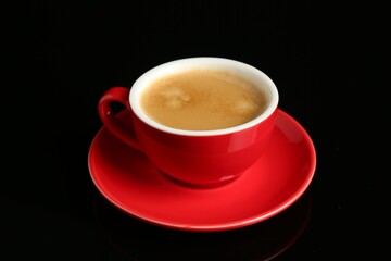 Red cup with coffee on black background, closeup