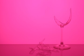 Pieces of broken wine glass against magenta background, space for text. Color tone effect