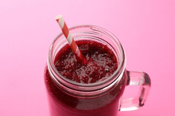 Fresh beetroot smoothie in mason jar on pink background, closeup