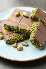 Pieces of Dubai chocolate bar with pistachios and knafeh on grey table, closeup