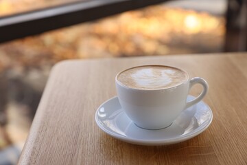 Cup of aromatic coffee on wooden table in cafe, closeup. Space for text