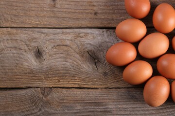 Many fresh eggs on wooden table, flat lay. Space for text