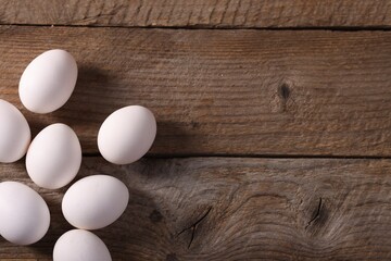 Many fresh eggs on wooden table, flat lay. Space for text