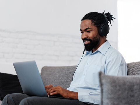 Relaxed Man Wearing Headphones Working From Home on Laptop