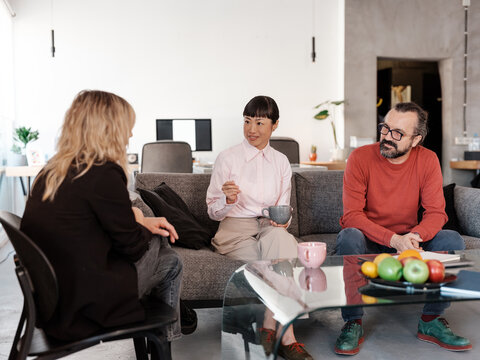 Three Colleagues Engaged in Informal Discussion in Modern Office