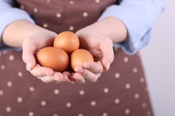 Woman with raw eggs on light background, closeup