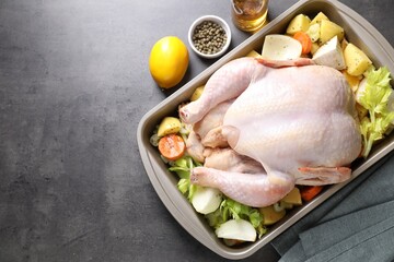 Raw turkey with different vegetables and spices on grey table, above view. Space for text