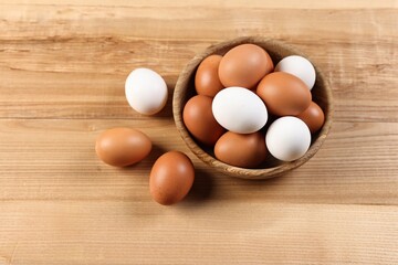 Raw eggs in bowl on wooden table, closeup