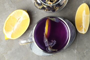 Delicious butterfly pea flower tea with lemon on gray textured table, flat lay