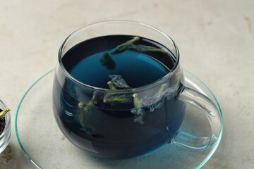 Delicious butterfly pea flower tea in cup on gray textured table, closeup