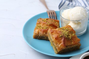 Tasty baklava with chopped nuts and scoops of ice cream on white table, closeup