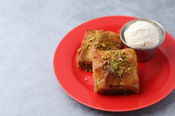 Tasty baklava with chopped nuts and scoop of ice cream on grey table, closeup. Space for text