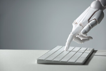 Artificial intelligence. Robot hand using keyboard at light table against grey background, closeup....