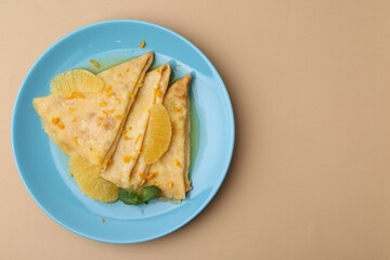 Plate with tasty crepes Suzette on beige table, top view. Space for text